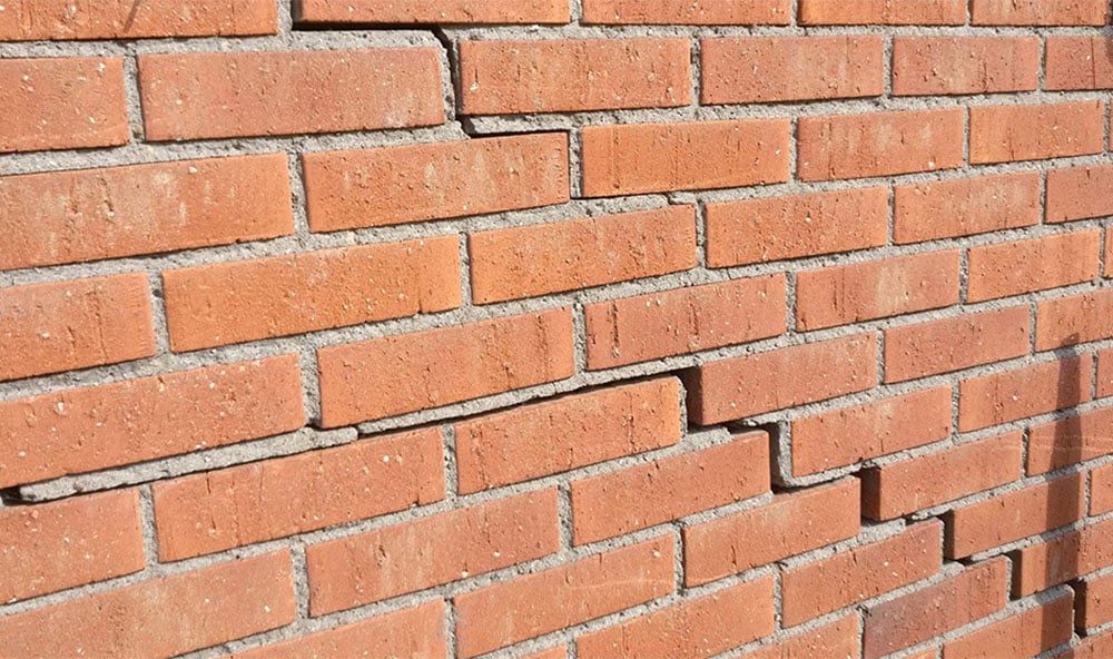 En spricka i ett trappsteg i tegelverket på en yttervägg i ett bostadshus
